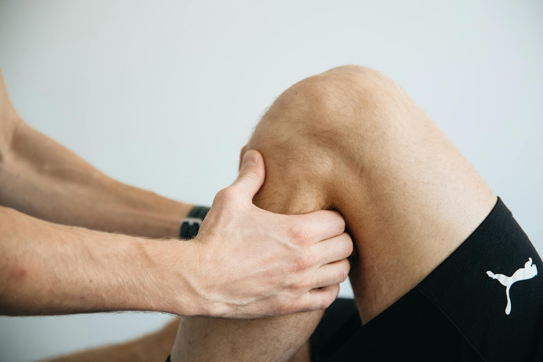 Fizjoterapeuta masuje bolące kolano pacjenta podczas rehabilitacji
